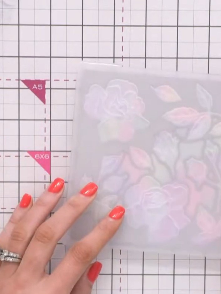 Step 1: Place the holographic paper into the Elegant Rose embossing folder and die set. Run it through your die-cuttin
