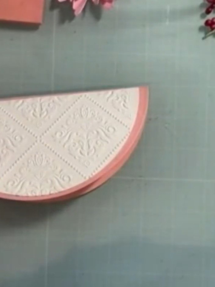 Step 12: Take the larger semi-circle piece with the pink border and emboss it using the Renaissance wallpaper embossing