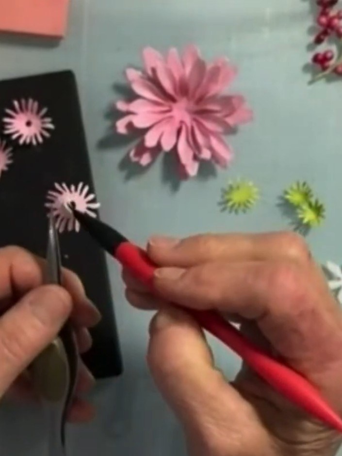 Step 8: Using tweezers to hold the die-cut flower pieces, pierce a hole through the centre of each pink gerbera daisy 