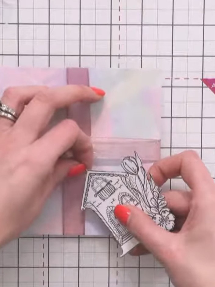 Step 6: Attach the decorative tag to the front of the pink gift box using tape or glue. Position the tag centrally on 