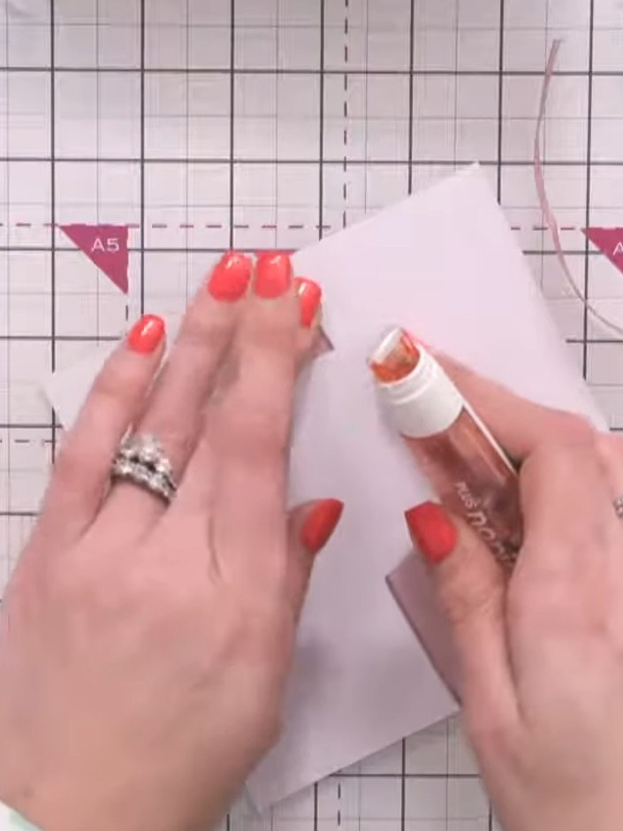 Step 2: Position and attach the first ribbon horizontally across the front of the box using glue or tape. Ensure the r