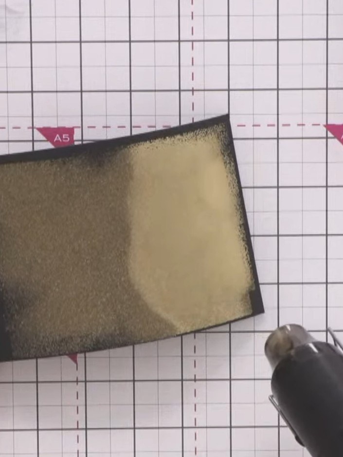 Step 8: Heat set the metallic gold powder with the heat gun, moving it across the surface until the powder is fully me