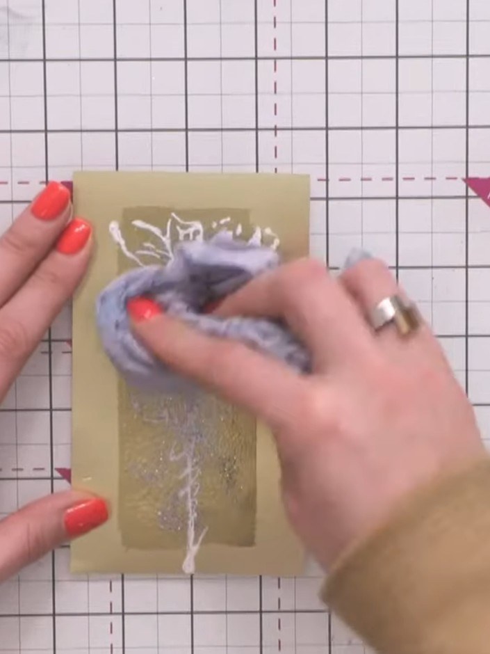 Step 12: Take your sticky ink pad and apply it generously over the embossed area on the gold cardstock. Sprinkle thick 