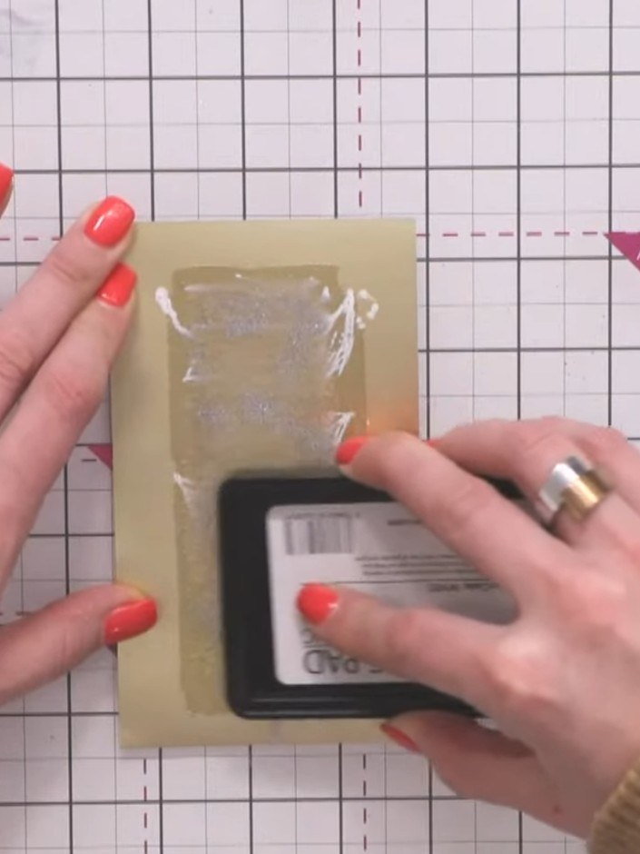 Step 13: Heat set the embossing powder using a heat gun, moving it evenly over the surface until the powder melts and b