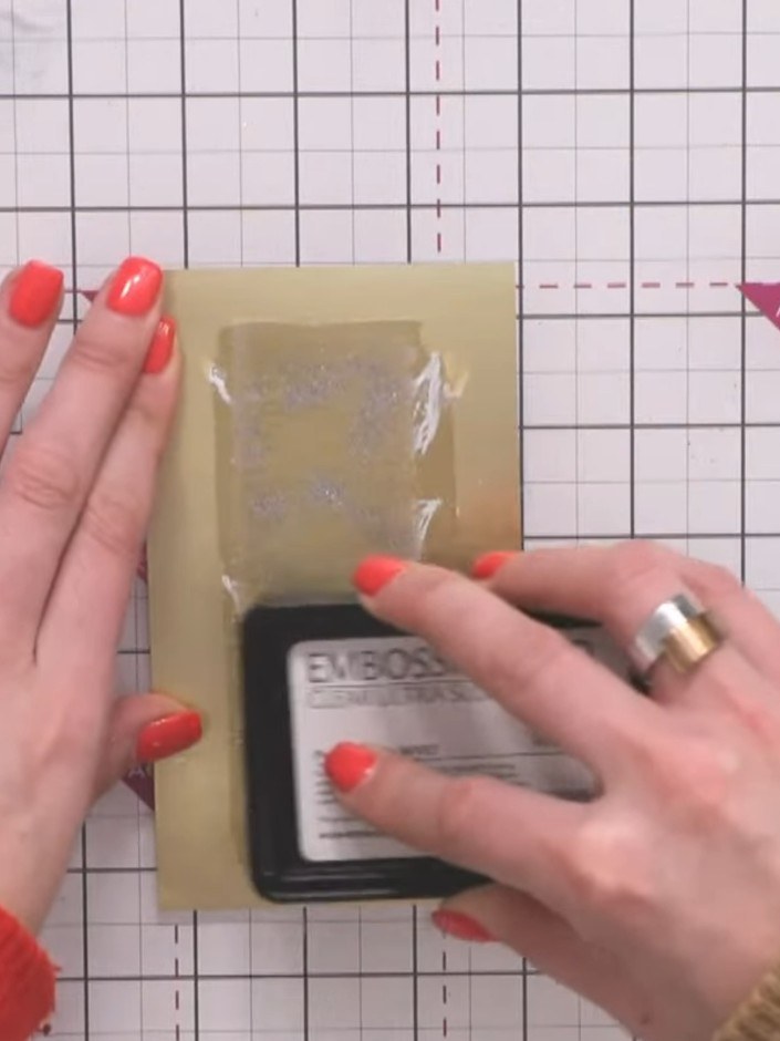 Step 14: Whilst the embossed surface is still warm, press the white-inked flower stamp firmly into it to create an impr