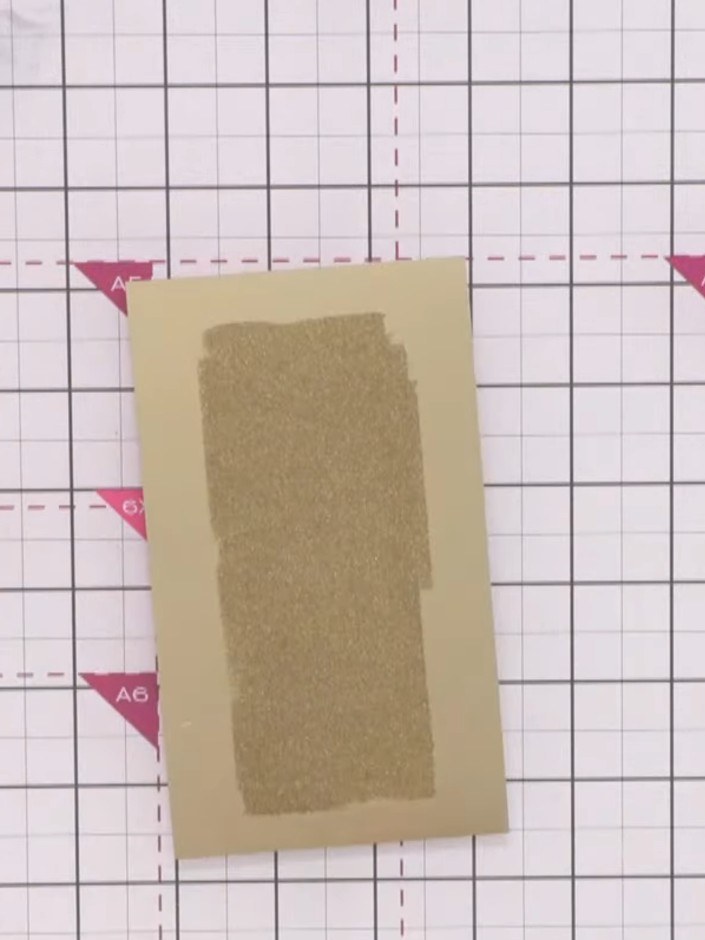 Step 8: Use the heat gun to heat set the layered powder mixture on the gold cardstock panel. Move the heat gun evenly 