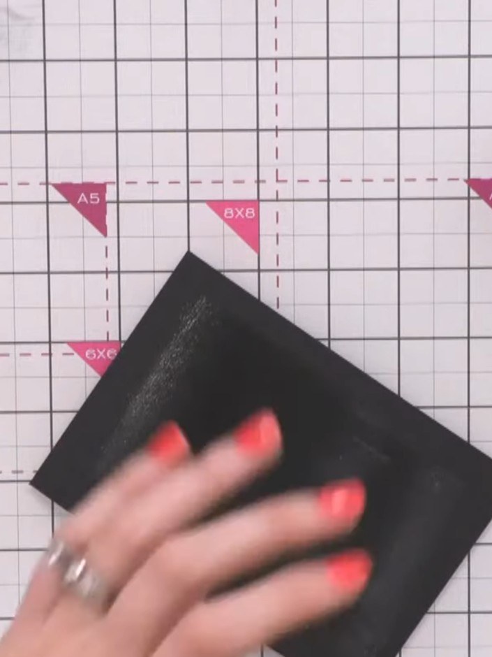 Step 7: Tap off the excess embossing powder from the black cardstock to remove any powder that hasn't stuck to the adh