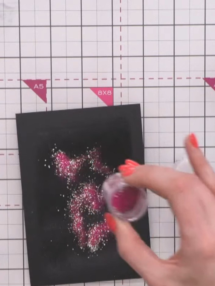Step 9: Gently tap off the excess glitter from the black cardstock to reveal your design. Hold the card over your craf