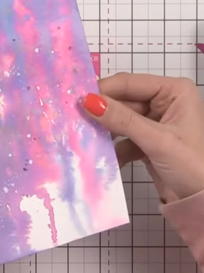 Step 6: Add white splatter details across the watercolour background using white paint or ink. Then add black splatter