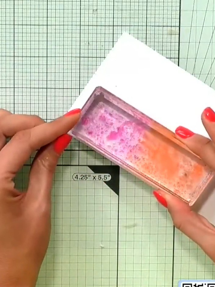 Step 1: Apply pink ink to the top portion of an acrylic block and orange ink to the bottom portion, creating an ombre 