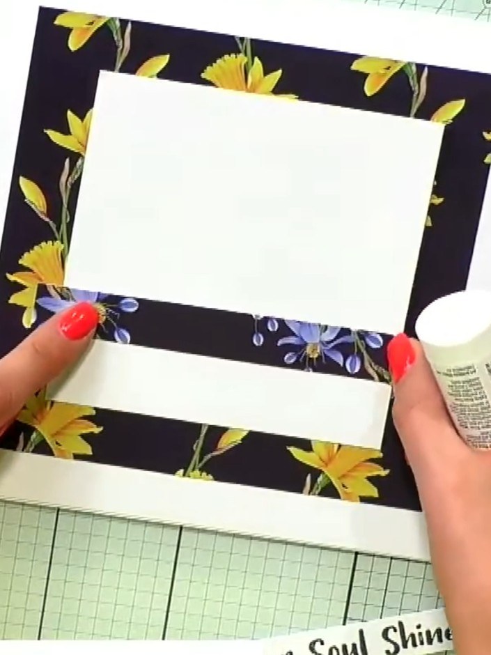 Step 4: Glue each white strip down flat to the card base, positioning them horizontally across the floral patterned pa