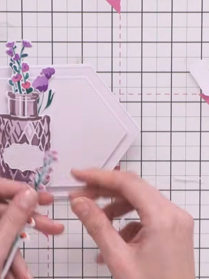 Step 10: Arrange the flower sprigs and vase pieces on your hexagonal card base, layering some elements behind and some 
