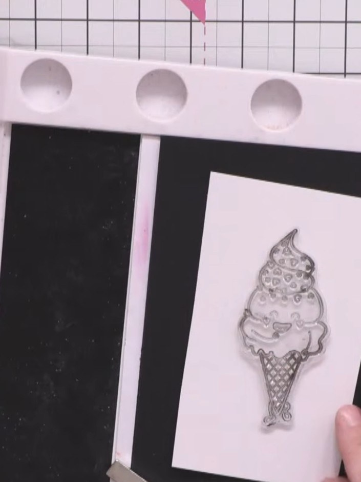 Step 7: Position the ice cream character stamp on the white card panel in front of the black curtain backdrop to creat