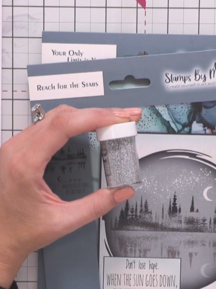 Step 3: Using the stamp glitter moonlight pen, add foliage elements from the stamp set around your moon and water scen