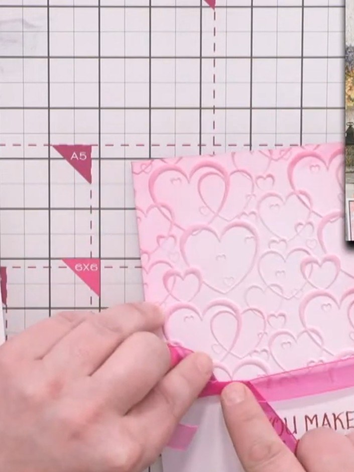 Step 10: Amarra un listón rosa sobre la línea donde se unen el panel con embossing y la tarjeta base blanca, y asegúralo con un nudo.