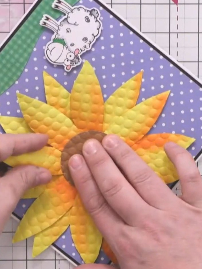 Step 13: Adhere the dimensional sunflower to the card front using glue. Position the circular sentiment in the centre o