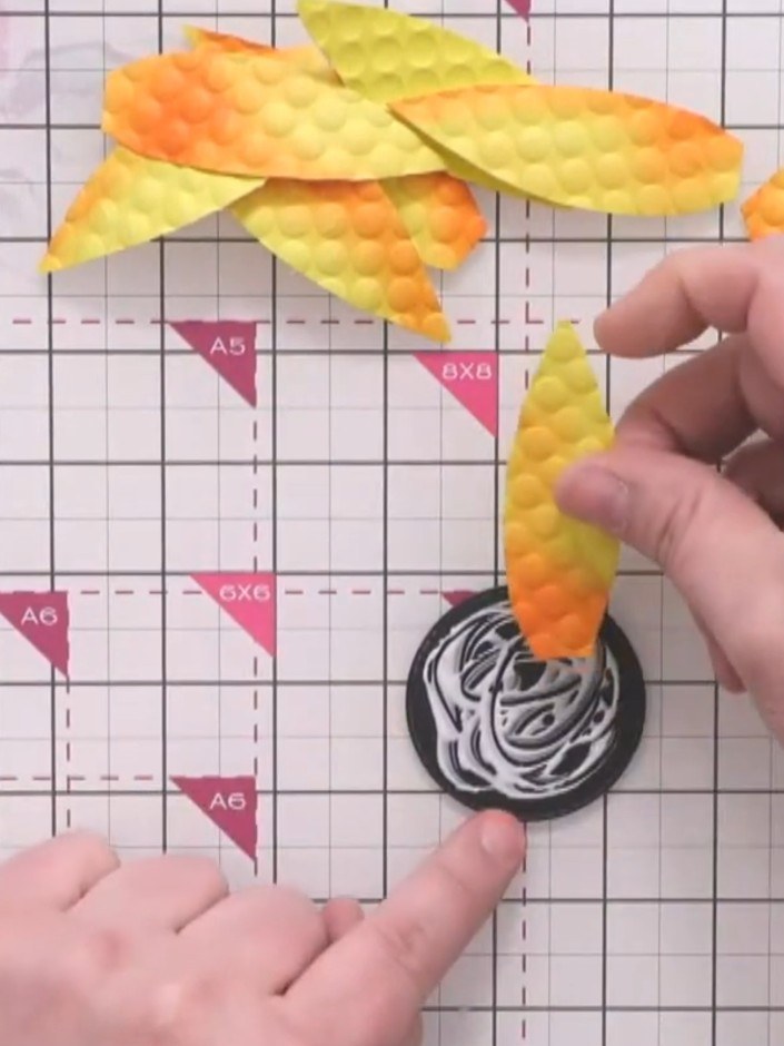 Step 8: Glue the first layer of four embossed petals around the black circle centre, spacing them evenly to form a cro