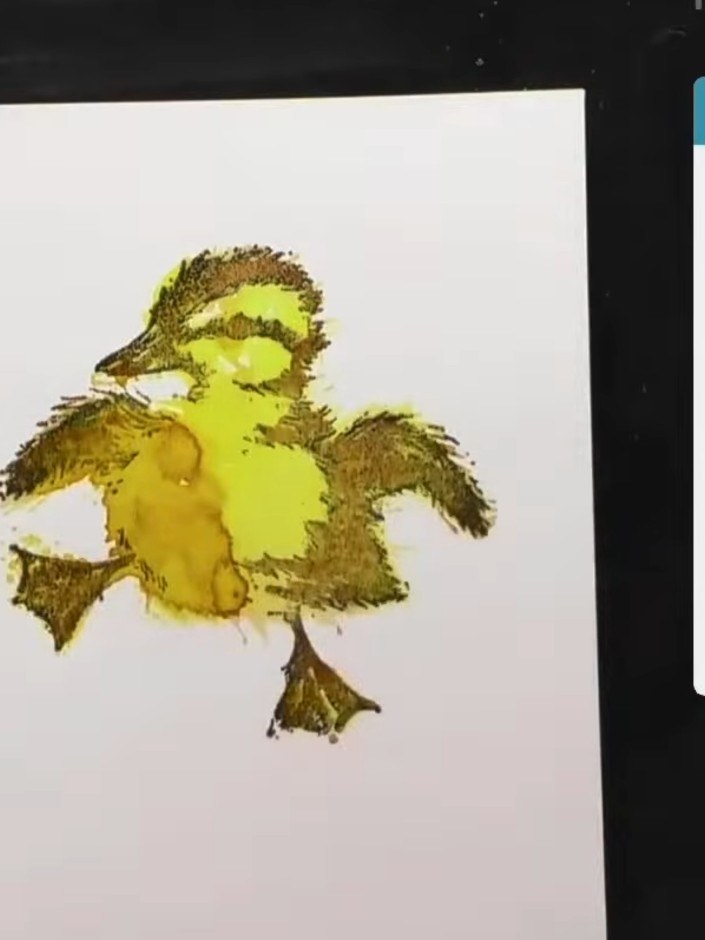 Step 11: Spray a small amount of blue ink around the duckling's feet to create a puddle effect, suggesting the duckling