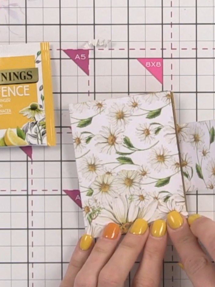 Step 14: Glue the fussy-cut floral elements to the front cover of your mini album. Add additional decorative paper pock