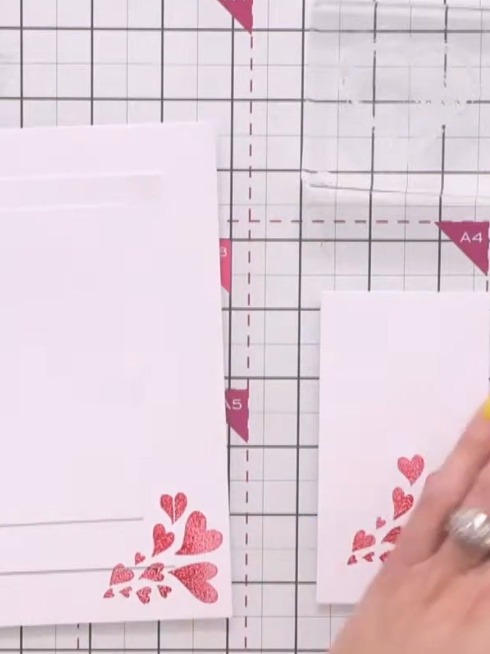 Step 2: Stamp the scatter of hearts design in pink ink onto the outer white card layer. Press firmly to transfer the p