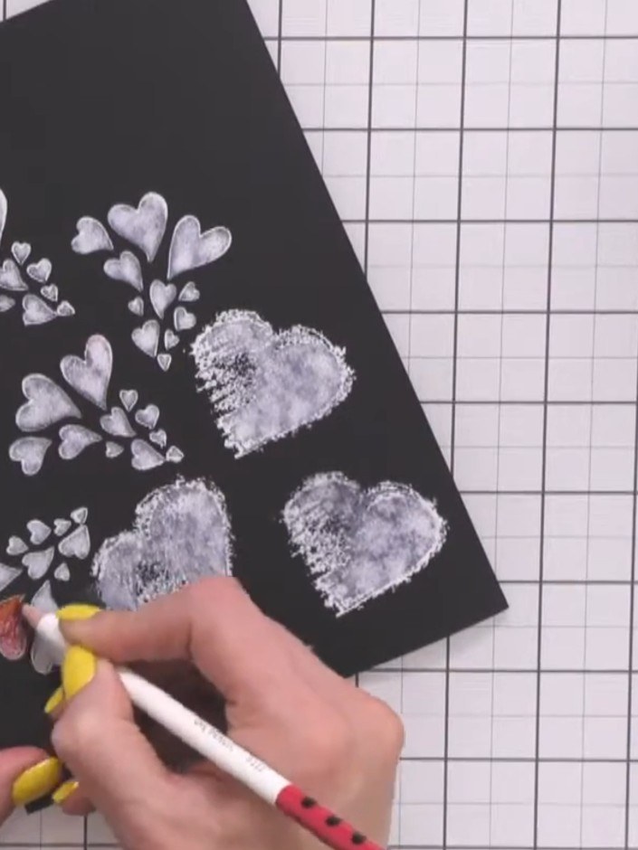 Step 3: Colour over the white stamped heart designs on the black cardstock using coloured pencils. Work carefully to f