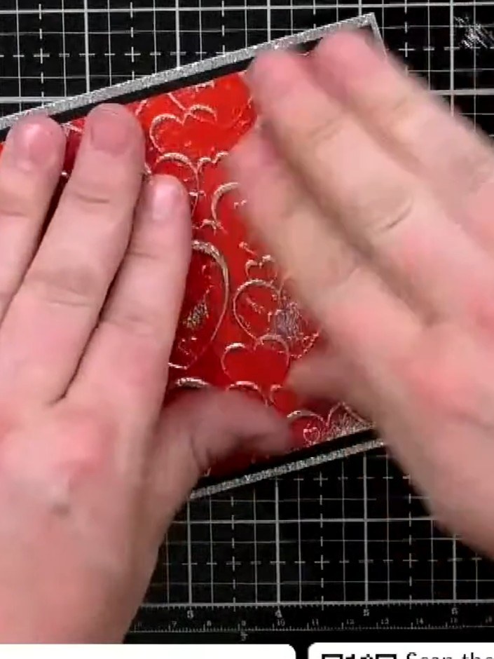 Step 5: Attach the black-mounted embossed panel to the silver glitter card base using both tape runner and glue for a 