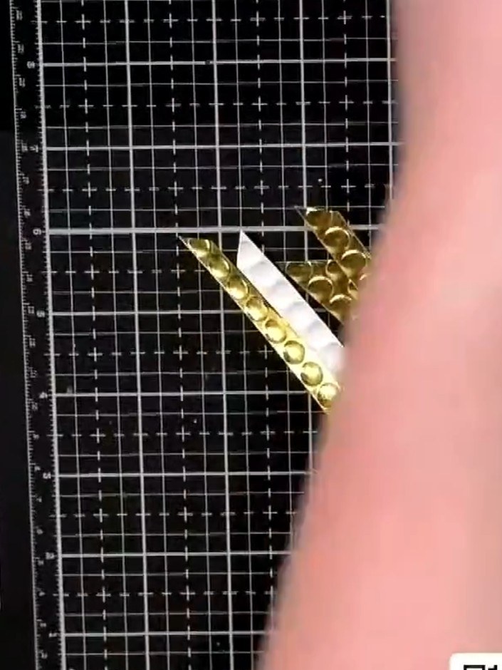 Step 3: Arrange the gold and black embossed strips on your card base, overlapping them at different angles to create v