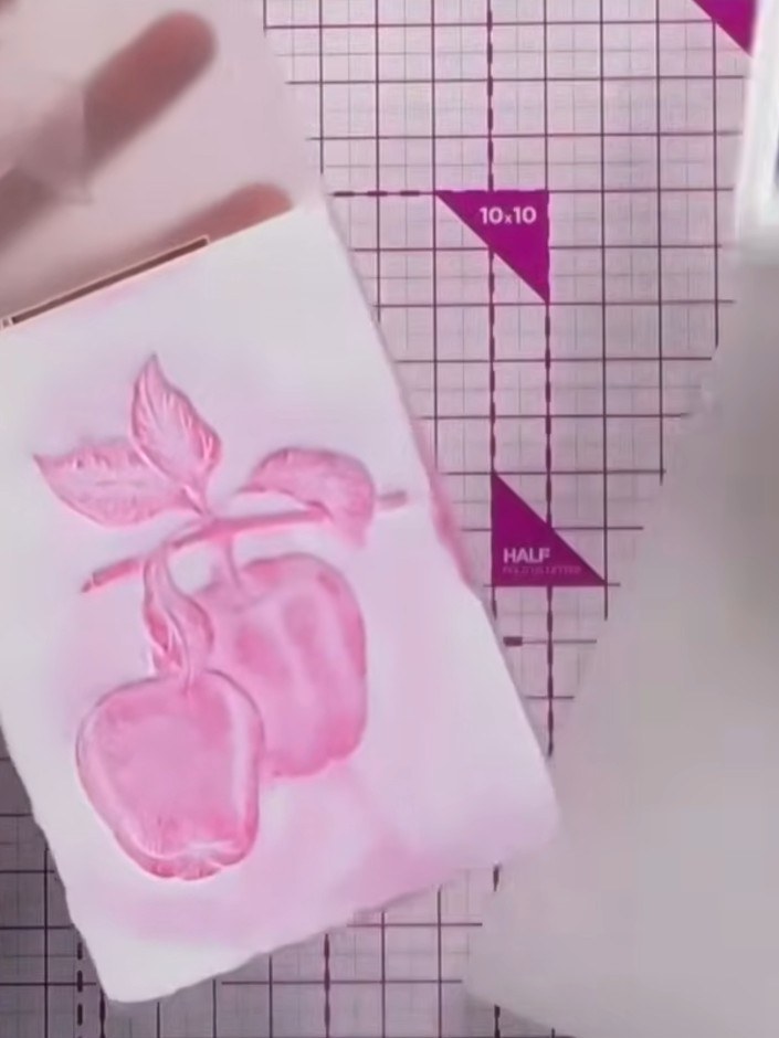 Step 3: Besprühe den eingefärbten Prägefolder leicht mit Wasser, um einen Aquarelleffekt auf dem rosa Cardstock zu erzeugen.