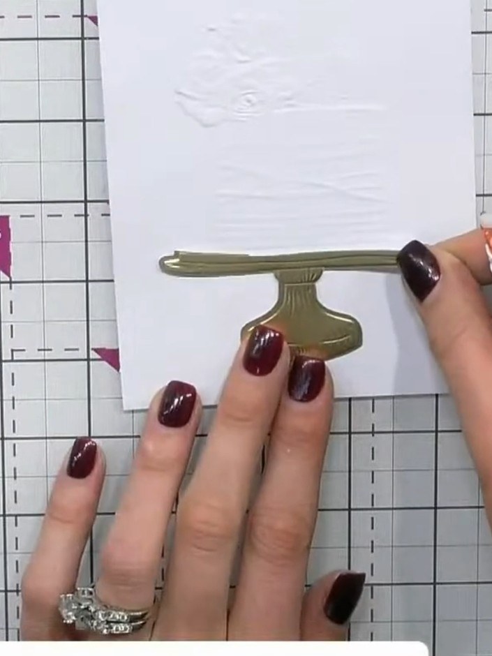 Step 6: Apply adhesive to the back of the white cake piece and adhere it onto the gold embossed pedestal base, alignin