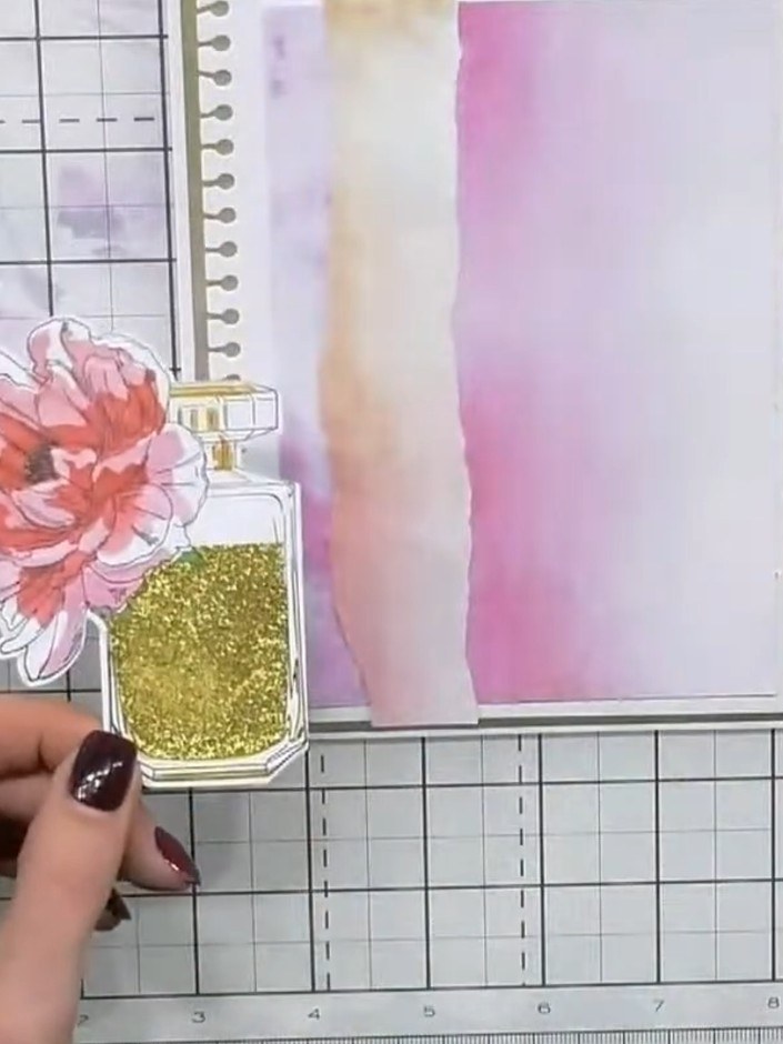 Step 7: Take a previously made perfume bottle flower element with a pink flower and gold glitter bottle. Attach it to 