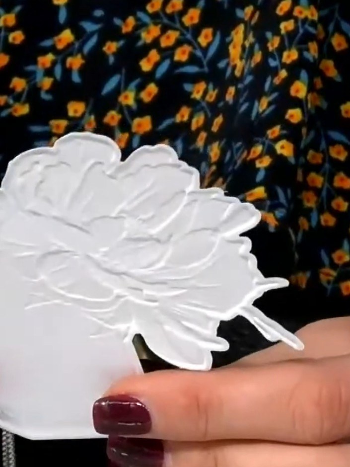 Step 8: Run the white die-cut flower piece through the 3D embossing folder to add dimensional texture and detail to th