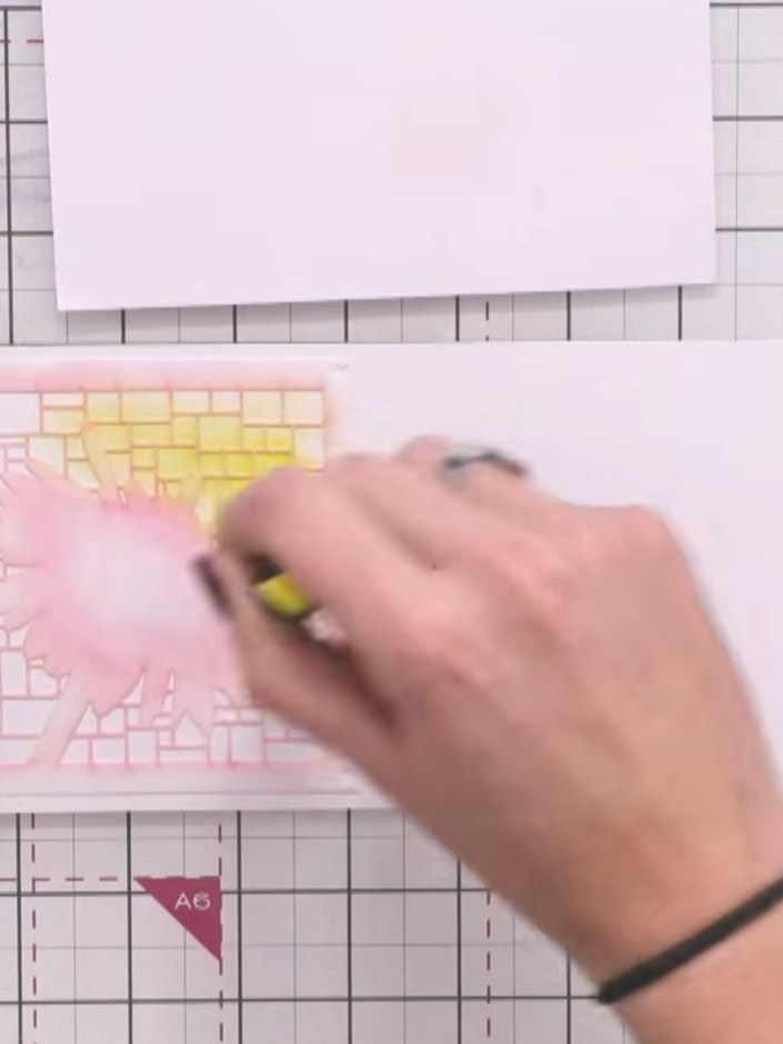 Step 3: Apply yellow ink through the stencil using a brush, dabbing it over the flower area to create a soft halo effe