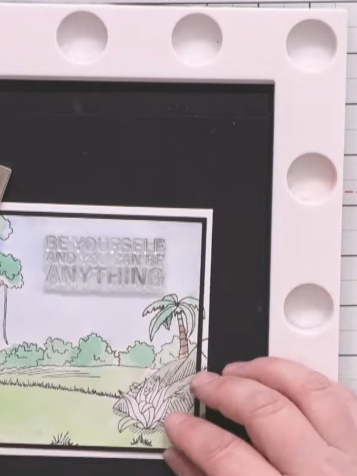 Step 11: Stamp a large sentiment onto white card using black ink and position it in the sky area of your scene. Use a s