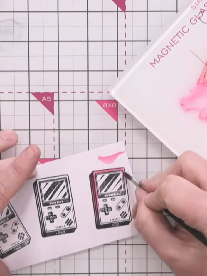 Step 11: Using a water brush or damp paintbrush, watercolour the stamped game consoles with Magenta ink. Leave some are