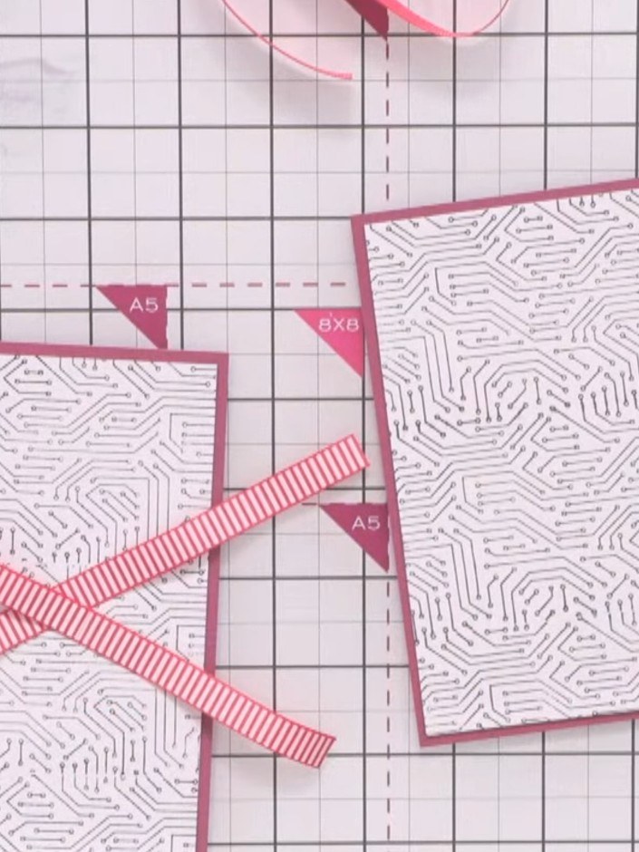 Step 6: On one of the card panels, arrange strips of pink and white striped ribbon in a cross pattern. Secure each rib