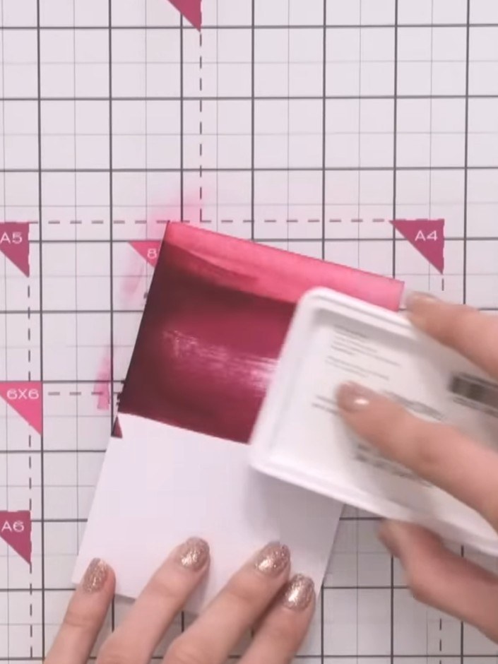 Step 2: Pasa la almohadilla de tinta rosa directamente sobre la cartulina blanca con trazos sueltos y suaves para crear un efecto de lavado de tinta.