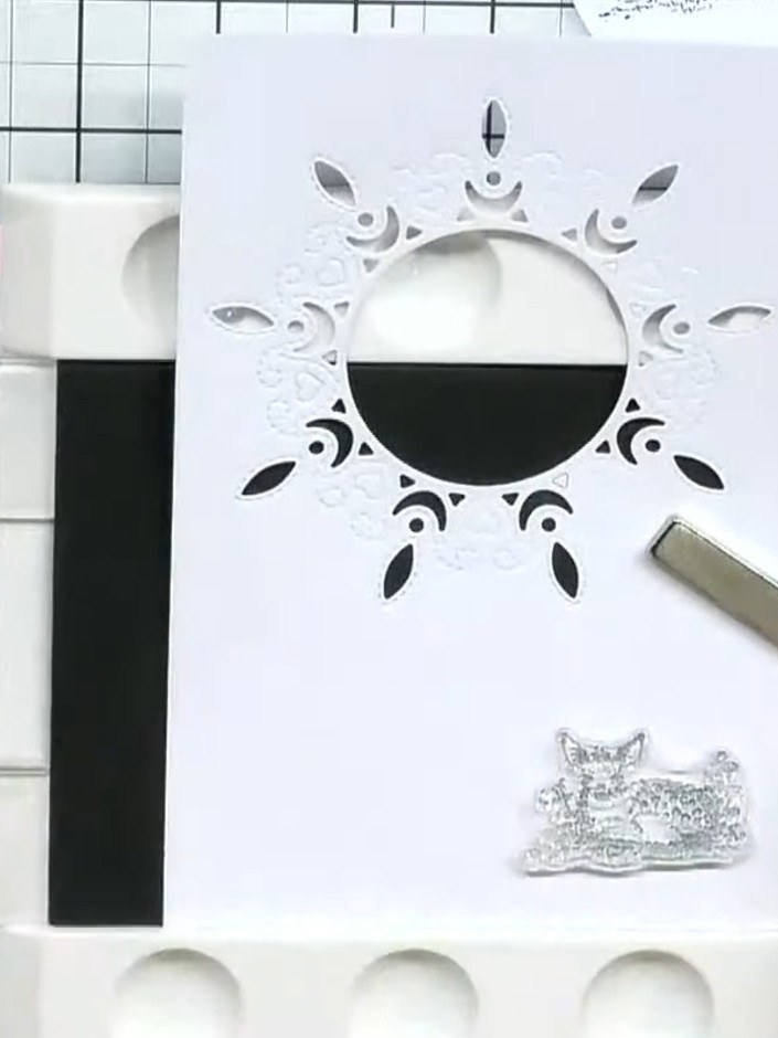 Step 5: Position the completed frame over the black card base, ensuring the stamped scene is visible through the centr