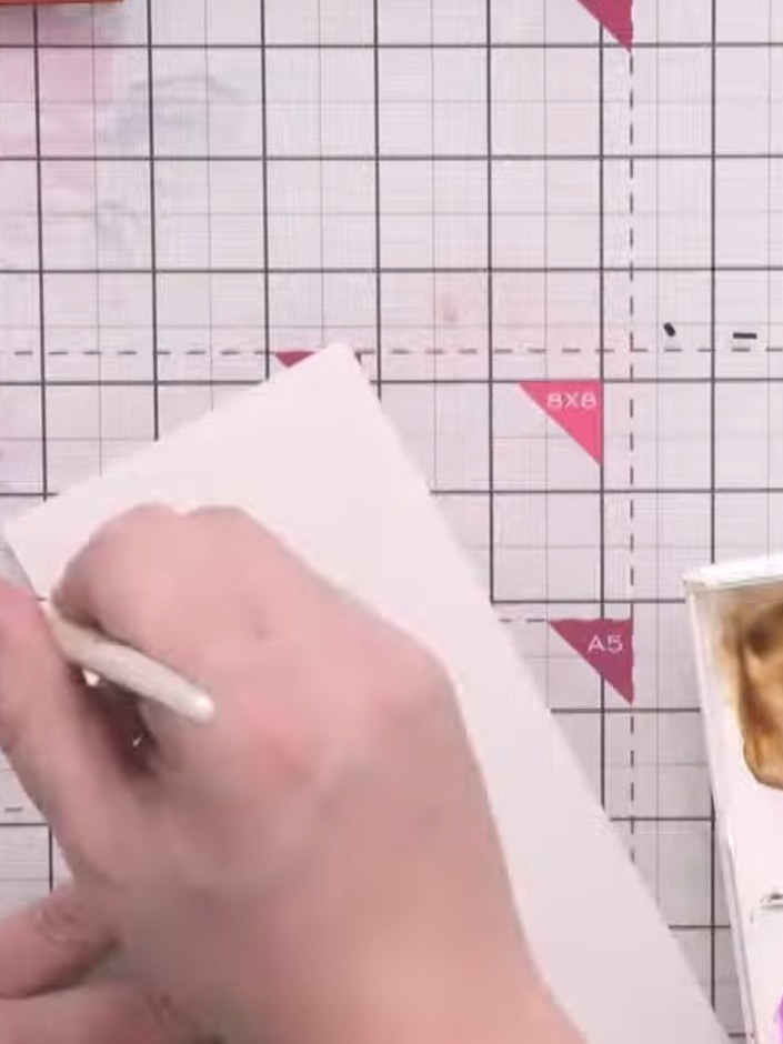 Step 12: Wet a strip of watercolour card with clean water using a brush. Apply purple watercolour in bands across the w