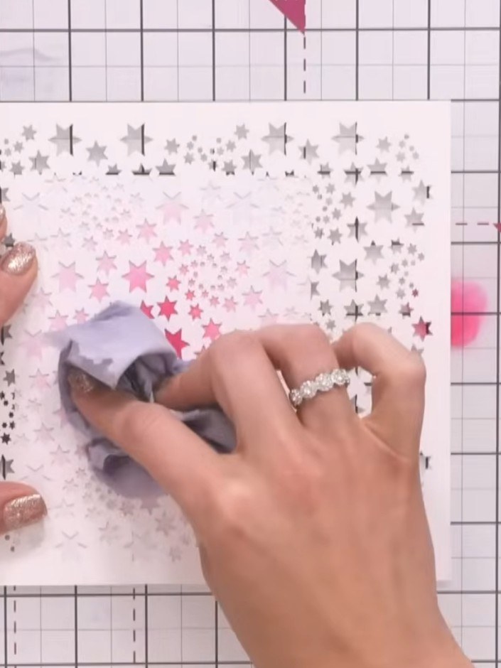 Step 4: Push a damp tissue through the stencil openings to lift colour away from the centre, revealing the white star 
