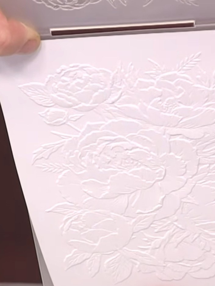 Step 2: Using a white ink pad, tap it repeatedly across the embossed floral design to fill in all the raised areas. En