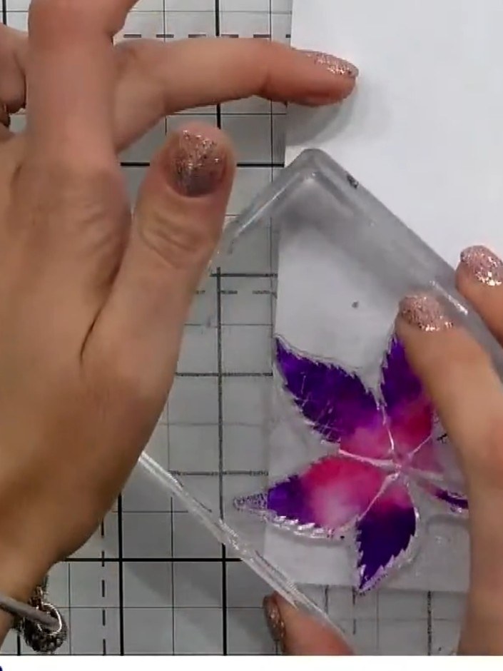 Step 5: Carefully lift the stamp away from the card to reveal the watercolour wash effect with purple and pink tones b