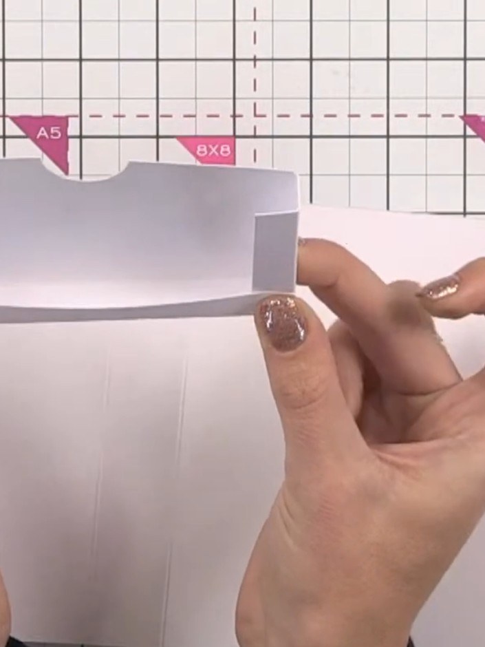 Step 12: Apply glue to the tabs on the first pocket piece and attach it to the inside base of the book. Hold the pocket