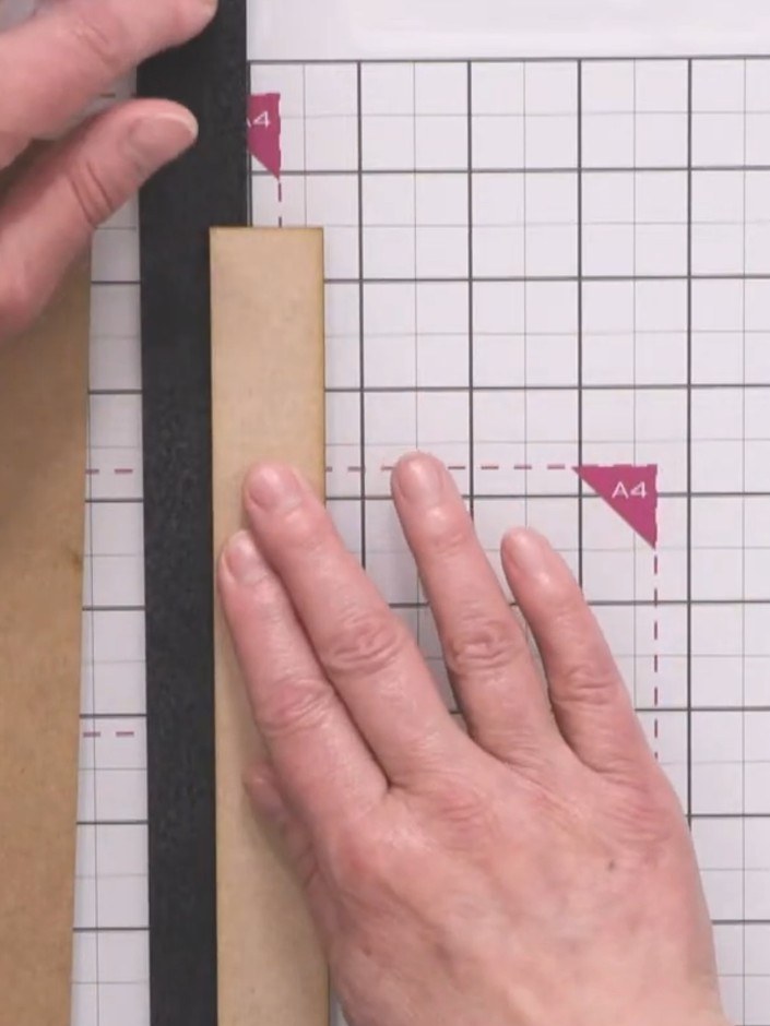 Step 4: Attach the black construction tape along the spine area of the cardboard piece. Burnish it down firmly with th