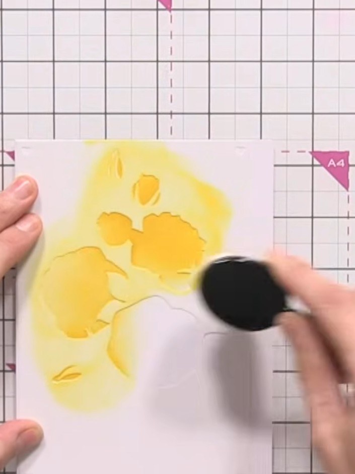 Step 3: Position stencil number one over your white card. Using the yellow ink pad, tap colour through the stencil ope
