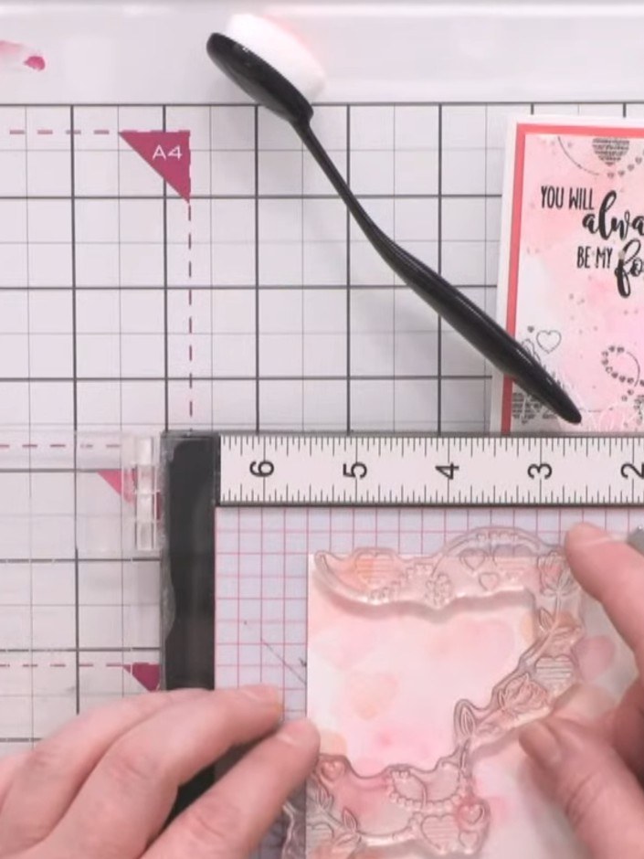 Step 4: Stamp the love word stamp inside one of the heart shapes using black ink to create a focal point on your card.