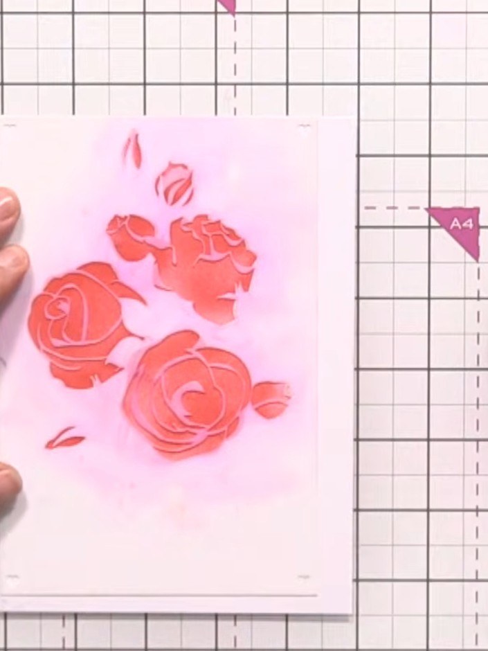 Step 4: Position the second rose stencil over your design and ink through with the same red ink pad. Press firmly with