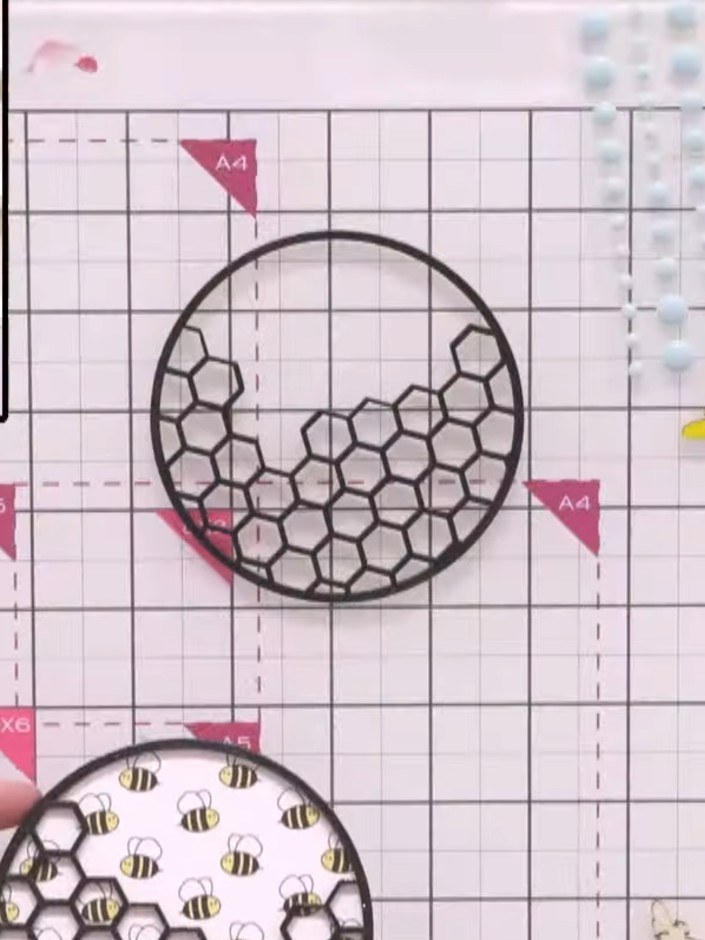 Step 8: Mat the circular honeycomb ply embellishment with the bee pattern paper, ensuring the bee details are visible 