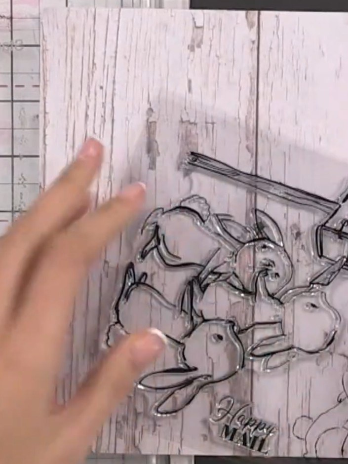 Step 1: Stamp the rabbit family image onto wood grain patterned paper using black ink. Position the stamp to show the 