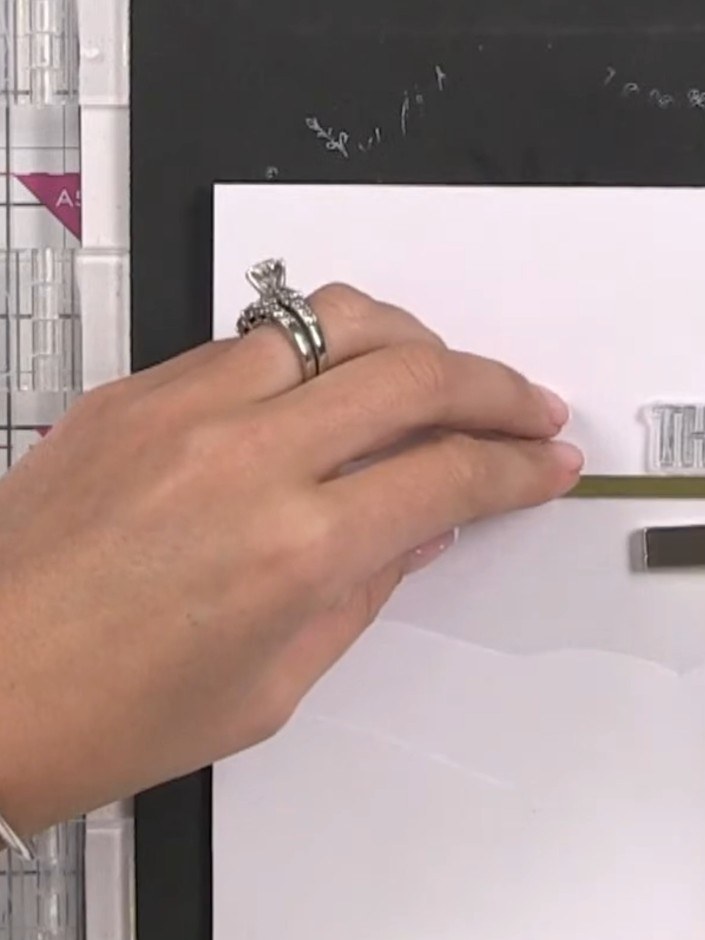 Step 12: Stamp a sentiment such as 'THANKS' onto the top section of the card front using a clear stamp and black ink. P