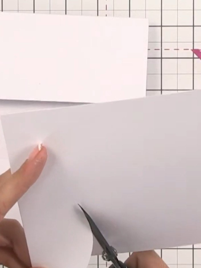 Step 5: Cut freehand hill shapes from white card using scissors to create landscape layers. Hold the card steady and c